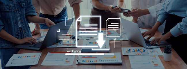 A diverse team collaborates in an office space, using laptops and smartphones to download data and analyze project reports amid a productive and creative atmosphere. Trope