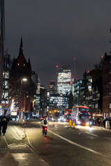 Naklejka premium London streets at night glow with car headlights and reflections on wet roads, creating lively, atmospheric cityscape