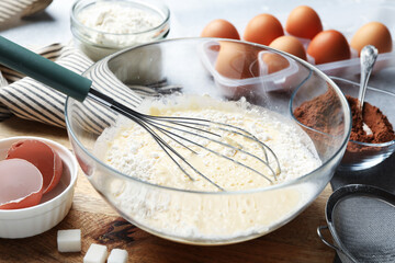 Different ingredients for dough and whisk on table, closeup