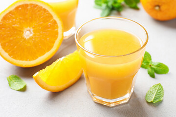 Fresh orange juice, mint and fruits on light table, closeup