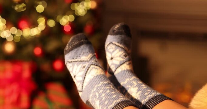 Woman wearing cozy socks against Christmas lights, closeup