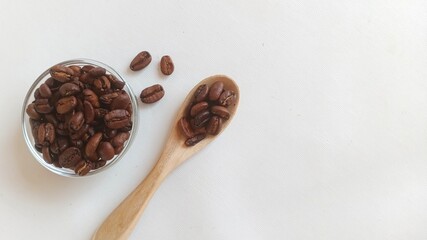 Close up of roasted coffee bean on the bowl and spoon, isolated white background. With copy space