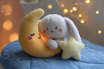 Cute rabbit plush toy and moon cushion in soft light with a star ornament at a cozy indoor setting during evening hours