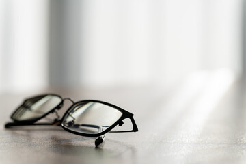 窓辺の光と影に佇むスタイリッシュな黒縁眼鏡