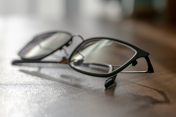 窓辺の光と影に佇むスタイリッシュな黒縁眼鏡