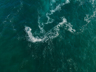 Aerial drone photo of ocean waves crashing against rocky shoreline. Dynamic naturel seascape with textured water,foam patterns and coastal rock viewed from above. minimalist and abstract.