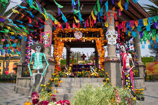 Altar tradicional de D&iacute;a de Muertos en kiosco de Tepotzotl&aacute;n, Estado de M&eacute;xico, decorado con flores de cempas&uacute;chil, papel picado y figuras de calavera, representando la tradici&oacute;n cultural mexicana