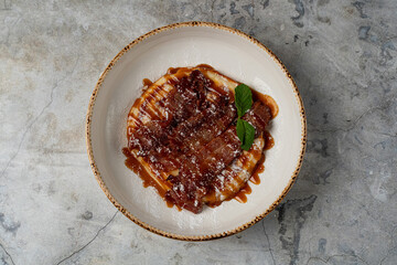 Indulgent layers of caramel and chocolate glisten atop a creamy base, garnished with fresh mint. This dessert captivates the senses with its rich flavors and artistic presentation