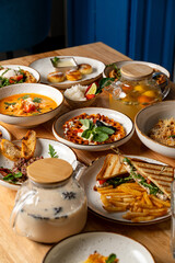 A charming table is adorned with a variety of colorful dishes including soups, salads, and crispy snacks, inviting friends to gather and enjoy a delicious meal together