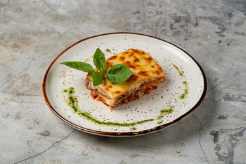 Savory lasagna rests on a rustic plate, showcasing layers of pasta, meat, and rich tomato sauce....