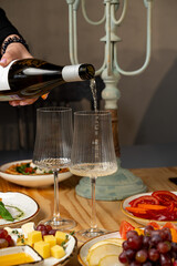Friends gather around a beautifully set table, enjoying exquisite wine being poured into elegant glasses. Delicacies and fresh ingredients surround them, creating a vibrant atmosphere