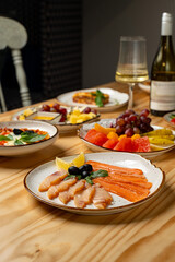 A delightful assortment of fresh salmon, vibrant fruits, and white wine sets the scene for a relaxing evening. The warm atmosphere invites enjoyment and celebration