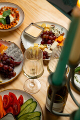 A variety of colorful plates filled with fresh fruits, cheeses, and dips are arranged on a wooden table. Elegant glasses hold sparkling drinks, creating a festive atmosphere for sharing