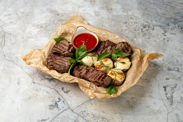 Juicy grilled steak is served with creamy melted cheese and a side of vibrant red sauce. Fresh basil leaves add a touch of green, creating a delightful culinary scene