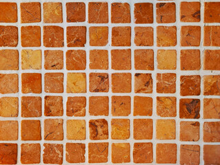 Natural stone mosaic tile texture. Square tesserae in earthy, orange and brown with veining and light-colored grout. Small marble slab cladding for interior wall, bathroom, kitchen, patio, pool.	