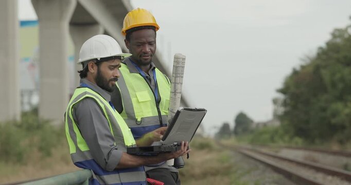A rail engineer and field technician inspect the railway corridor while discussing zero emission solutions and green infrastructure strategies to reduce the network carbon footprint.

