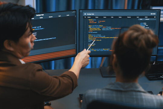 Smart IT developer looking at coding program application on computer screen of online website at back side, analyzing intelligent database system development on business marketing at office. Infobahn. - Powered by Adobe