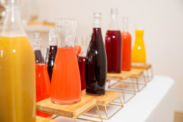 colorful juice in plain glass bottles at an event table, beautiful display of drinks