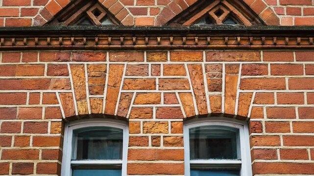 Victorian arched brick facade, ultra-detailed close-up of ornate masonry patterns and historical window arches showcasing classic architectural craftsmanship.