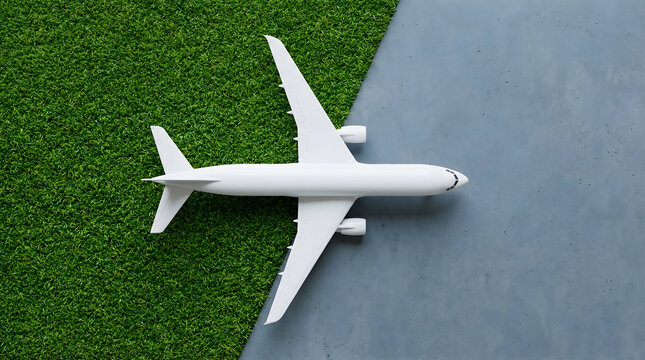 Top View of White Model Airplane on Green Grass and Concrete Background, Sustainable Aviation and Eco-Friendly Travel Concept