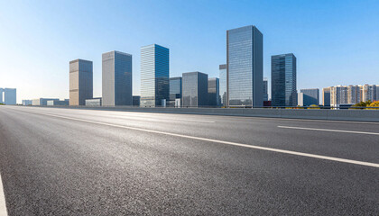 Empty wide asphalt road leading to modern glass skyscraper skyline under a clear blue sky