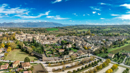 Aerial view of Bevagna medieval town center with city walls, gates, towers, Gothic churches with blue sky