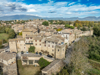 Aerial view of Bevagna medieval town center with city walls, gates, towers, Gothic churches with blue sky