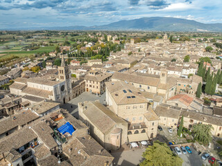 Aerial view of Bevagna medieval town center with city walls, gates, towers, Gothic churches with blue sky