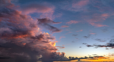 Naklejka premium Bright sunset with setting sun behind vivid orange and yellow clouds