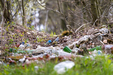 Pile of litter scattered in forest, plastic bottles and trash polluting the natural environment and disturbing the woodland landscape.