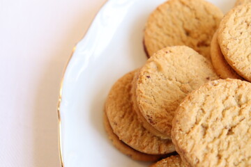 Close-up of cookies on a white background and a white plate. Pile of oatmeal fruit cookie. Tender biscuit, scone or oatcake. Raspberry soft cookie and snack and treats. Desserts and festive treats.