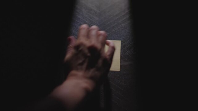 Slow motion close up footage of a hand writing out "Merry Christmas" on a paper note and placing it on a table. Shot in dramatic lighting for an impressive title or transition.