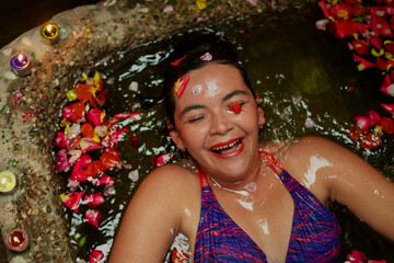 Woman laughing deeply while enjoying relaxing flower bath