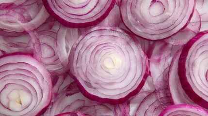 Obraz premium Close-up of layered, circular cuts of a red onion. The vibrant, pinkish-purple hues contrast against the white flesh, creating a dynamic texture