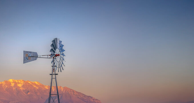 Windpump with a rugged golden mountain and cloudy sky background