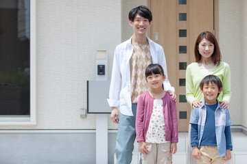 自宅の玄関先に立つ家族 © UTS