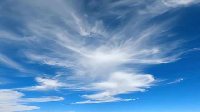 This mesmerizing video captures a dynamic expanse of vibrant blue sky adorned with various formations of white and grey clouds. Wispy cirrus and fluffy cumulus clouds gracefully drift, swirl, and slow