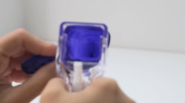 Gynecologist's hands operating a disposable plastic vaginal speculum on a white background