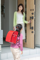 玄関先で見送る母親と娘