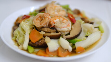 Stir-fried mixed vegetable with shrimps and shiitake mushroom isolated on white background.