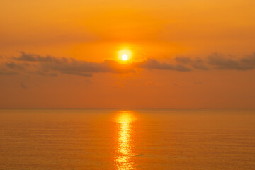 Obraz premium Nature sky breathtaking golden sunset over a calm ocean, with the entire sky and water bathed in brilliant shades of yellow and orange. Streaky clouds enhance the dramatic display of light 
