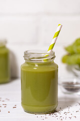 healthy superfood - green smoothie with chia seeds on white table, vertical closeup