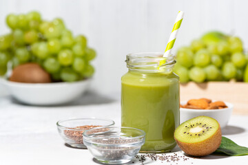 healthy superfood - green smoothie made from fruits and herbs on white background, closeup