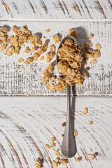 homemade granola in a spoon on a white background, vertical