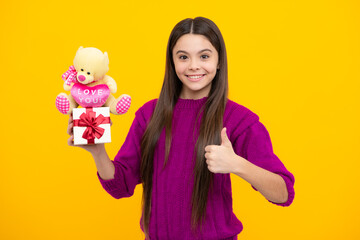 Teenager child holding gift box on yellow isolated background. Gift for kids birthday. Christmas or New Year present box. Valentines day.