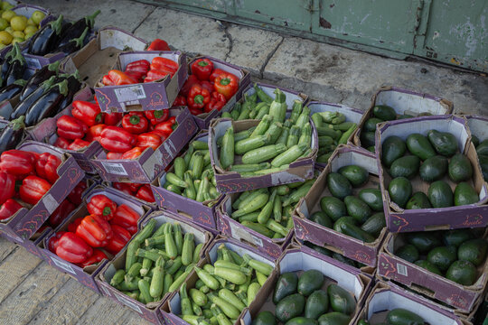 a lot of paprika, zucchini, abogado sold in boxes on the ground at the market in east jerusalem