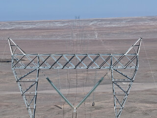 Long row of high-voltage towers for 220kv electric transmission lines crossing the desert