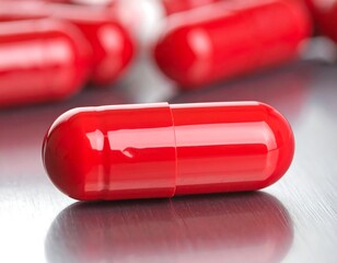 Close-up of a bright red capsule pill, others blurred in the background