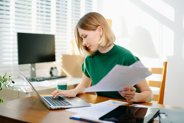 Business woman working from home office with laptop and documents. Remote work, productivity, paperwork and professional lifestyle concept