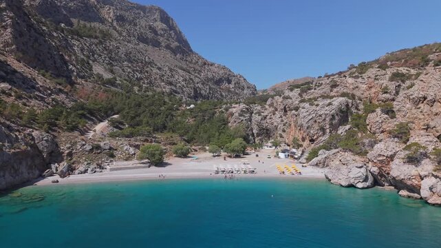Orbit view from the sea showcasing Achata Beach in Karpathos with stunning cliffs and raw island landscape in the background.